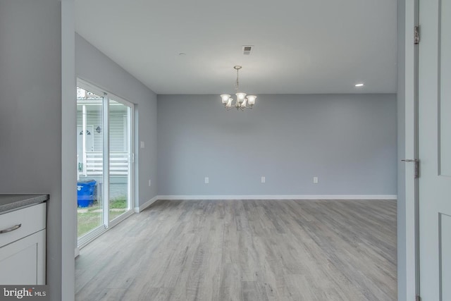 unfurnished dining area with light hardwood / wood-style floors and an inviting chandelier