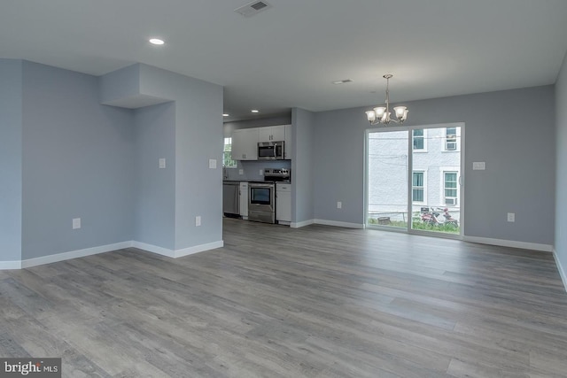 unfurnished living room featuring light hardwood / wood-style floors and an inviting chandelier