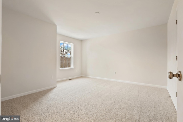 unfurnished room with baseboards, visible vents, and light colored carpet