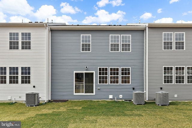 rear view of house with central AC and a yard