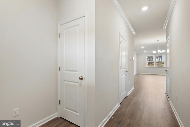 hall featuring dark wood-style flooring, crown molding, recessed lighting, an inviting chandelier, and baseboards