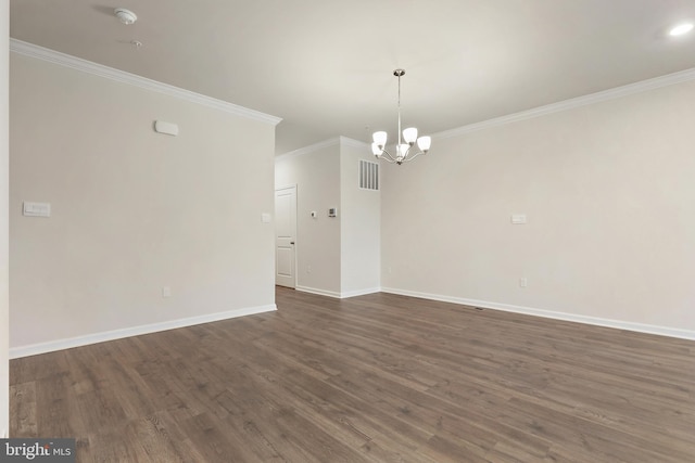 spare room featuring crown molding, dark wood finished floors, visible vents, an inviting chandelier, and baseboards