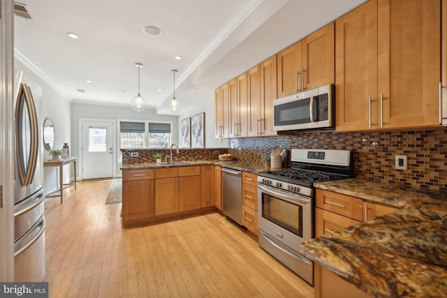 kitchen featuring hanging light fixtures, light hardwood / wood-style flooring, stainless steel appliances, sink, and dark stone counters