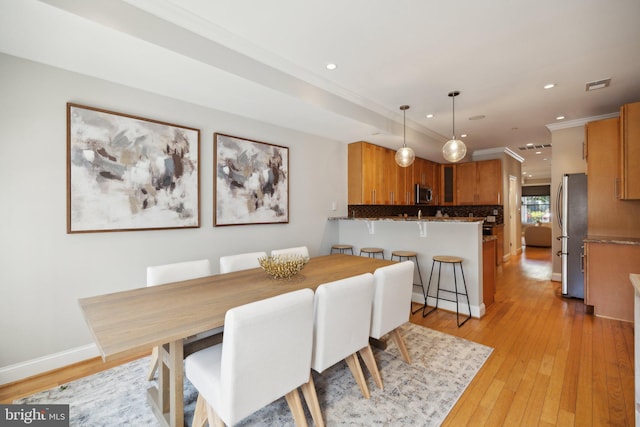 dining room featuring light wood-type flooring and crown molding