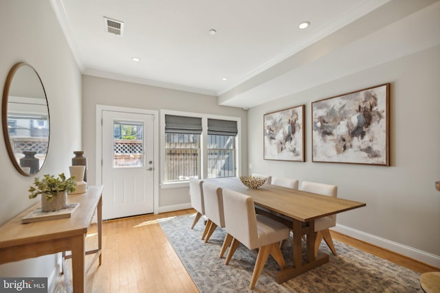 dining area with crown molding and light wood-type flooring