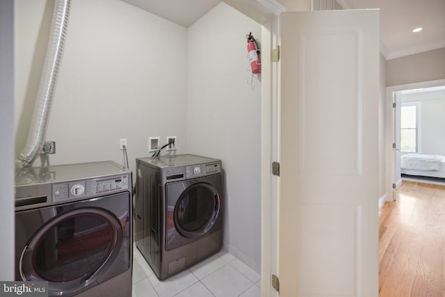 laundry room with crown molding, washing machine and dryer, and light wood-type flooring