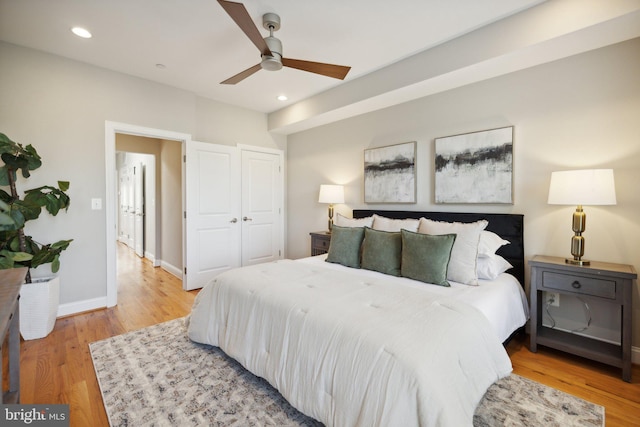 bedroom featuring light hardwood / wood-style flooring, ceiling fan, and a closet