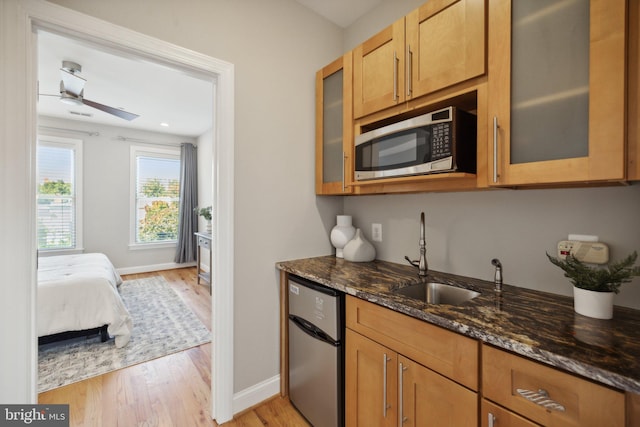 kitchen with light hardwood / wood-style flooring, stainless steel appliances, dark stone countertops, and ceiling fan