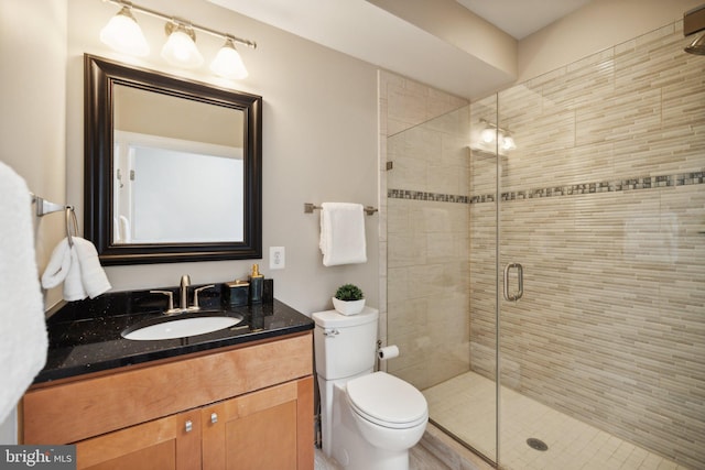 bathroom featuring vanity, toilet, and a shower with shower door