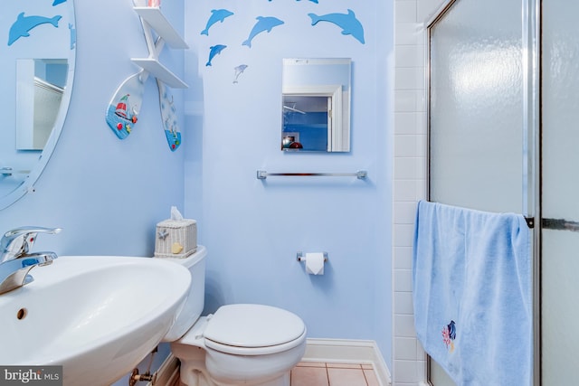 full bath with baseboards, toilet, a shower with door, tile patterned flooring, and a sink