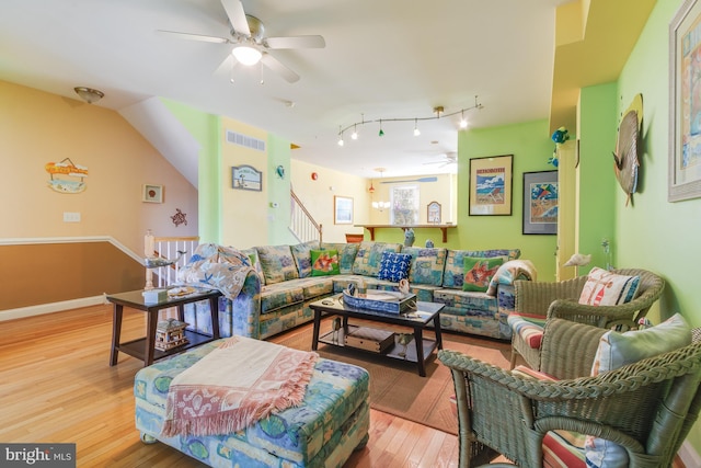 living area featuring a ceiling fan, baseboards, visible vents, and wood finished floors