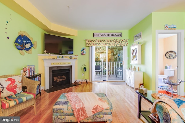 living room featuring a fireplace with flush hearth and wood finished floors