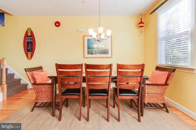 dining area with a notable chandelier, stairway, baseboards, and wood finished floors