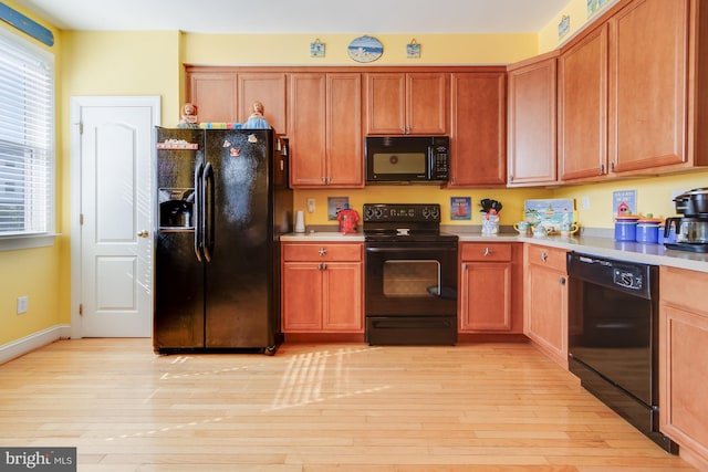 kitchen featuring brown cabinetry, light countertops, light wood-style flooring, and black appliances