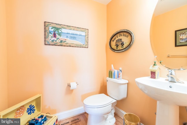 bathroom with visible vents, toilet, a sink, and baseboards