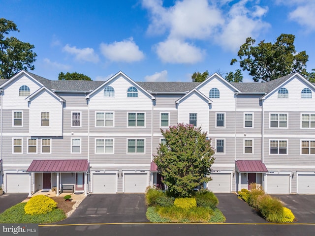 multi unit property featuring a garage, driveway, and a residential view