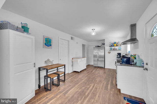 kitchen featuring wood finished floors, open shelves, freestanding refrigerator, white cabinetry, and exhaust hood