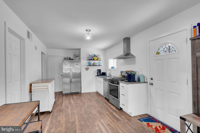 kitchen featuring white cabinetry, stainless steel appliances, wall chimney range hood, and dark wood-style flooring