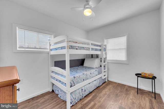 bedroom with multiple windows, wood finished floors, and baseboards