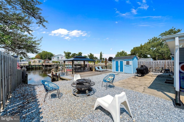 view of patio / terrace with a shed, a fire pit, a fenced backyard, and an outdoor structure