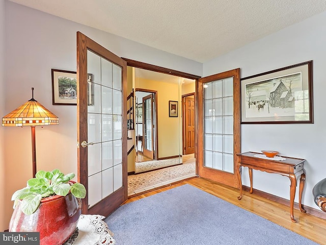 interior space featuring light wood-type flooring, a textured ceiling, and french doors