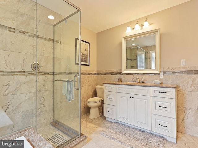 bathroom featuring vanity, toilet, tile walls, and a shower with shower door