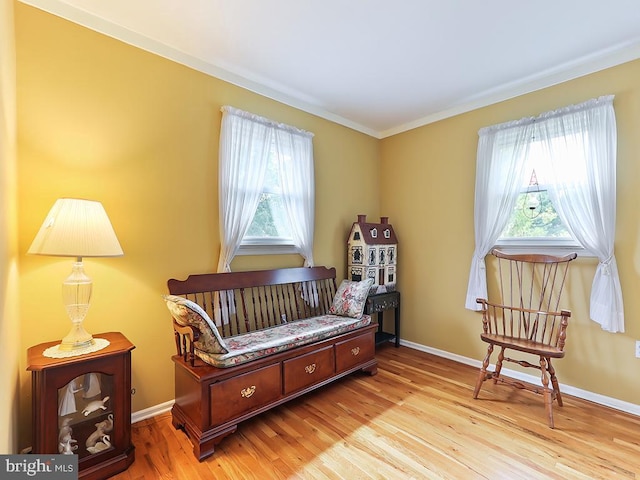 living area featuring a wealth of natural light, ornamental molding, and light wood-type flooring