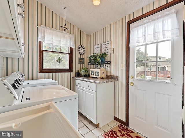 laundry room featuring plenty of natural light, cabinets, separate washer and dryer, and a textured ceiling