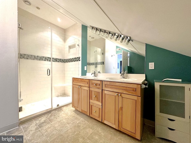 full bath with lofted ceiling, a stall shower, double vanity, and a sink