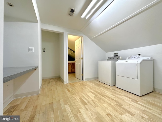 clothes washing area featuring light hardwood / wood-style flooring and washer and clothes dryer