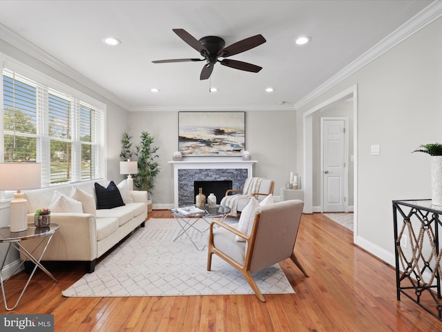 living area featuring baseboards, light wood-style floors, a fireplace, and crown molding