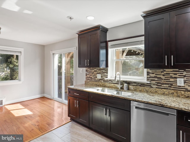 kitchen featuring stainless steel dishwasher, decorative backsplash, light stone countertops, and a sink