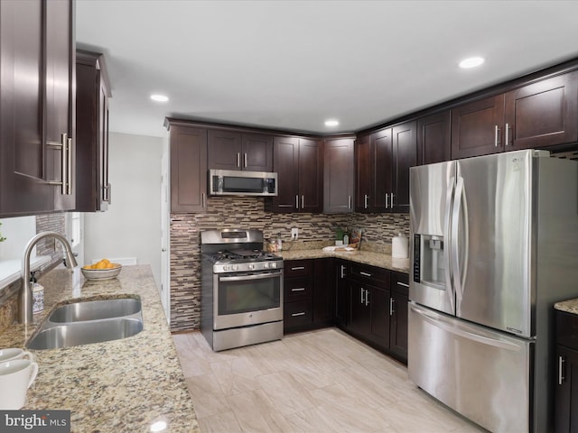 kitchen featuring a sink, light stone countertops, tasteful backsplash, and appliances with stainless steel finishes