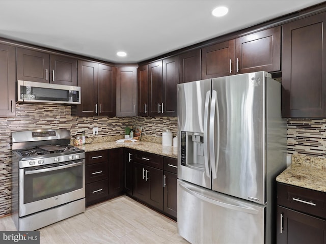 kitchen with light stone counters, recessed lighting, stainless steel appliances, dark brown cabinets, and tasteful backsplash