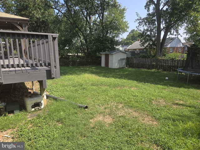 view of yard featuring a storage unit, a wooden deck, and a trampoline