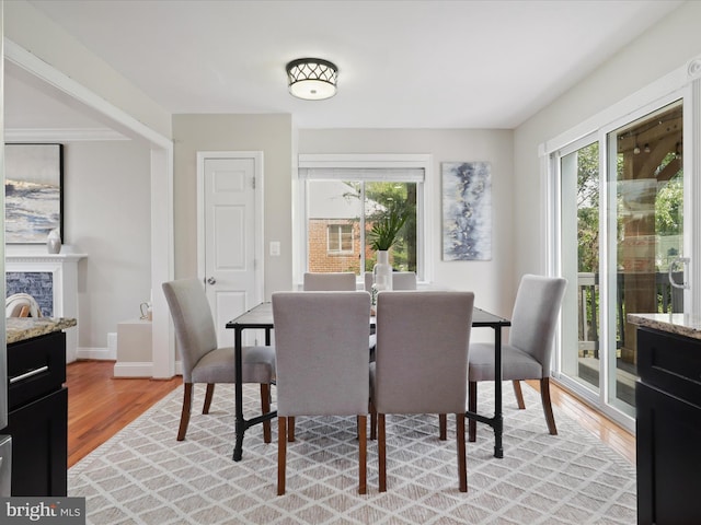 dining area featuring light wood finished floors, plenty of natural light, a fireplace, and baseboards