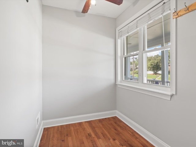 spare room with baseboards, wood-type flooring, and a ceiling fan