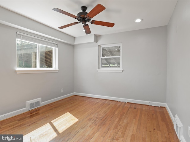 empty room featuring visible vents, ceiling fan, baseboards, and hardwood / wood-style flooring