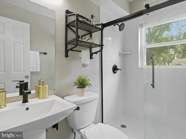 bathroom with a sink, tiled shower, and toilet