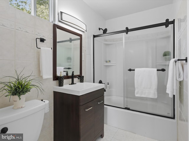 bathroom featuring toilet, shower / bath combination with glass door, tile walls, tile patterned flooring, and vanity