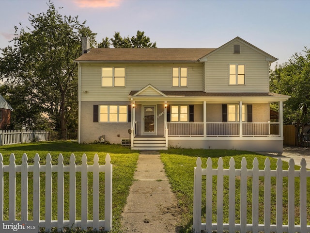 view of front facade with brick siding, a fenced front yard, a porch, and a front yard