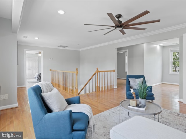 living area with wood finished floors, baseboards, visible vents, recessed lighting, and ornamental molding