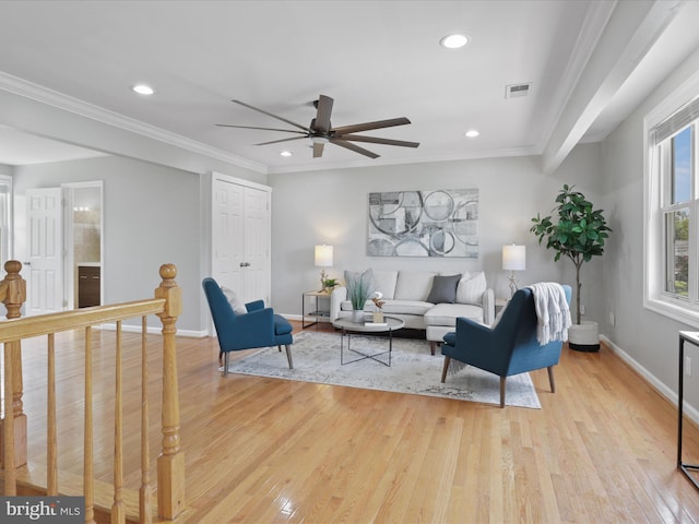 living area featuring crown molding, light wood-style floors, visible vents, and baseboards