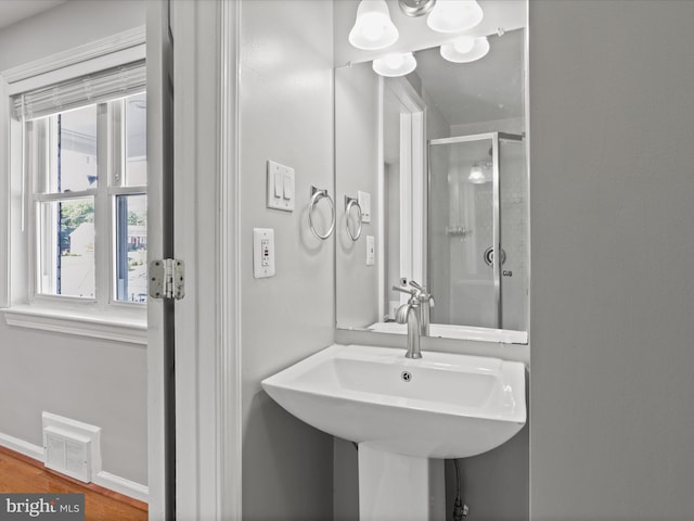 full bath with visible vents, a shower stall, baseboards, wood finished floors, and a sink