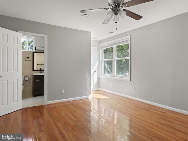 unfurnished bedroom with ensuite bath, sink, ceiling fan, and light hardwood / wood-style floors