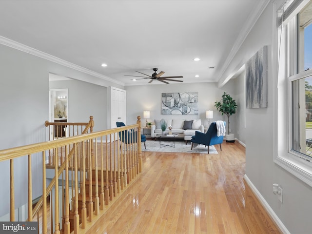 hall with baseboards, an upstairs landing, light wood-style floors, and ornamental molding