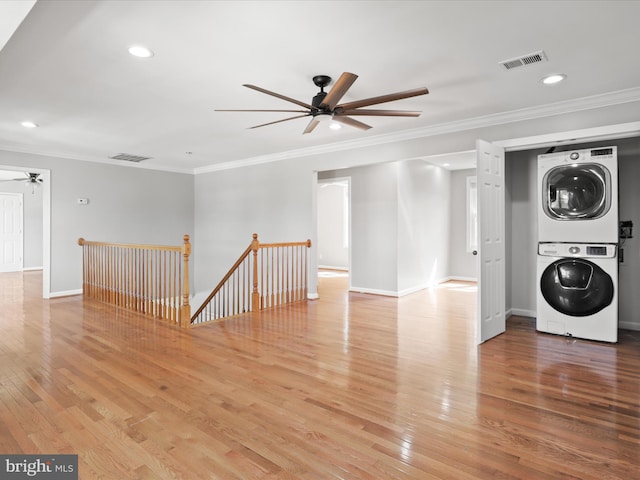 interior space with visible vents, crown molding, light wood-type flooring, and stacked washer and dryer