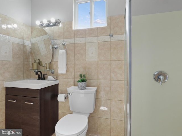 bathroom featuring vanity, tile walls, toilet, and a shower with shower door