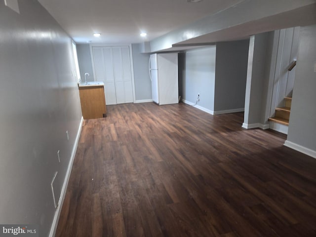 basement with dark wood-type flooring and white refrigerator