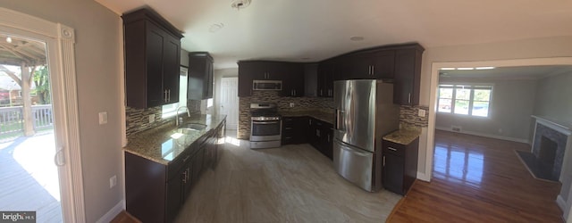 kitchen featuring light stone counters, stainless steel appliances, sink, dark wood-type flooring, and decorative backsplash